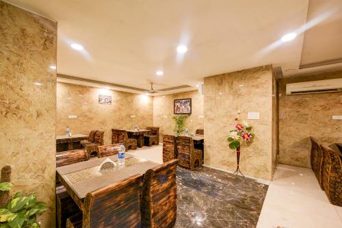 Balwood Suites Near Delhi Airport في نيودلهي: غرفة كبيرة بجدران حجرية وطاولة وكراسي
