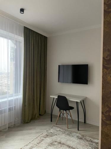 a room with a desk and a television on a wall at Больница Управ делами президента , IT Университет, Центр репродукции, Экспо Mega Silkway, Аэропорт in Prigorodnyy