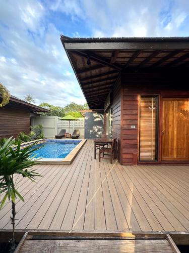 a wooden deck with a swimming pool and a house at GajaPuri Resort Koh Chang in Ko Chang