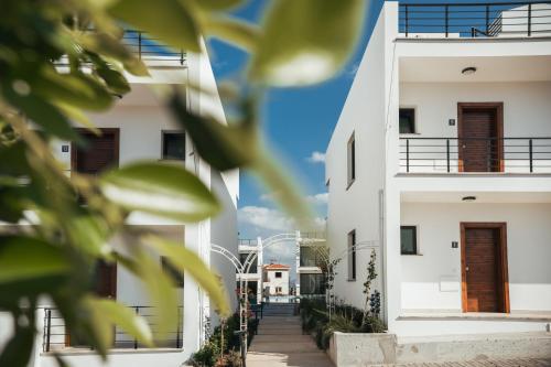 a view of two white buildings with green leaves at Pearl Island Holiday Homes in Kérynia