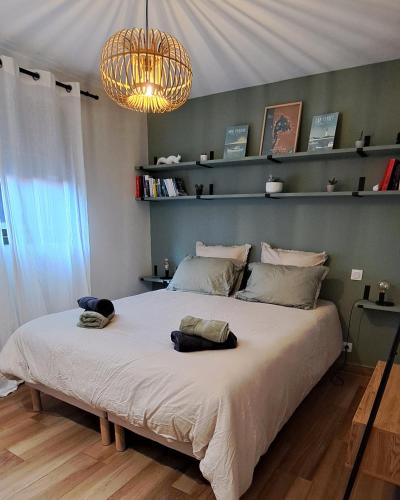 - une chambre avec un grand lit et un lustre dans l'établissement Villa Le Patio Bleu au calme, piscine chauffée, centre ville, à Arès