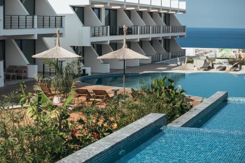 a swimming pool with chairs and umbrellas next to a building at Pearl Island Holiday Homes in Kérynia