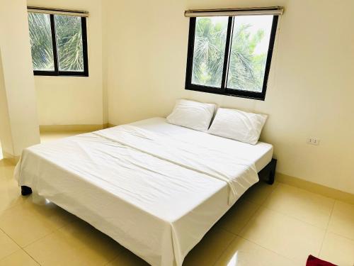 - un lit blanc dans une chambre avec 2 fenêtres dans l'établissement Spacer hotel, à Hạ Long