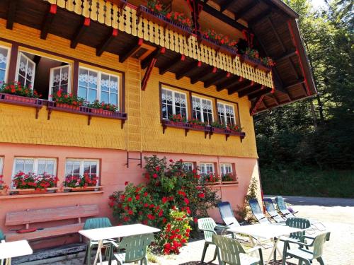 a building with tables and chairs and flowers in front of it at Quietly situated group house in the southern Black Forest with a gorgeous view in Todtmoos