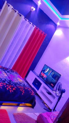 een slaapkamer met een bed en een tv op een tafel bij appartementmarcus in Cotonou
