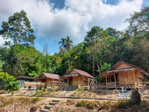 a group of huts in front of a forest at Samui Camping Farm in Laem Sor