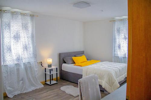 una piccola camera con letto e cuscino giallo di F&F Suites Ilsfeld - 3 Zimmer OG Apartment - Zentral mit kostenfreien Privatparkplätzen und WLAN a Ilsfeld
