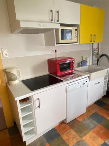 une petite cuisine blanche avec un micro-ondes rouge dans l'établissement Appartement Alsace Porte des Vosges, à Cernay