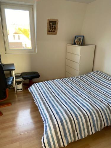 - une chambre avec un lit rayé et une fenêtre dans l'établissement Appartement Alsace Porte des Vosges, à Cernay