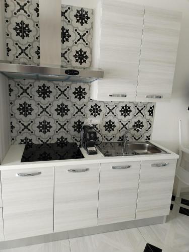a kitchen with white cabinets and black and white wallpaper at Mare D'amare in Porto Cesareo
