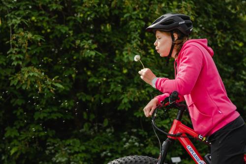 a young girl on a bike eating a d flower at Lapland Hotels Luostotunturi & Amethyst Spa in Luosto