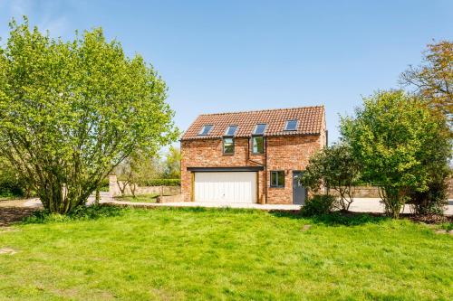 a brick house with a garage and two trees at The Loft - Rural setting with parking in Bishop Monkton