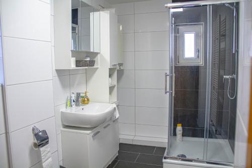 bagno bianco con lavandino e doccia di F&F Suites Ilsfeld - 3 Zimmer OG Apartment - Zentral mit kostenfreien Privatparkplätzen und WLAN a Ilsfeld