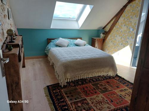 a bedroom with a bed with a window and a rug at Les Chaumes Violettes-Chambres & Table d'hôtes à la campagne, Berry in Cluis