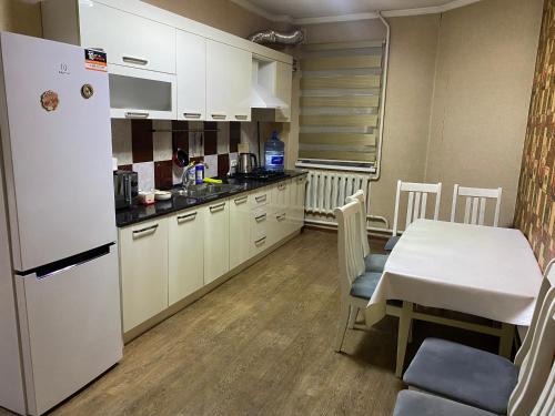 a kitchen with a table and a white refrigerator at Hostel 4U in Bishkek