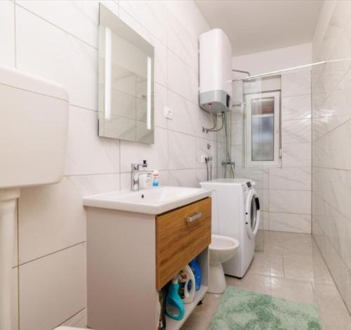 a white bathroom with a sink and a toilet at Kapetanova kuća in Novi Vinodolski
