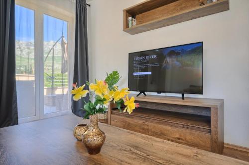 a living room with a tv and a vase with flowers at RELAX apartment Split area with private jacuzzi on terrace with mountain view in Srinjine