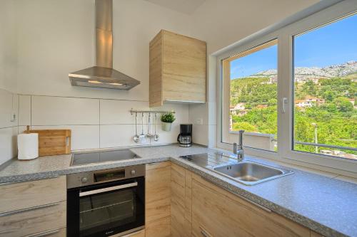 a kitchen with a sink and a large window at RELAX apartment Split area with private jacuzzi on terrace with mountain view in Srinjine