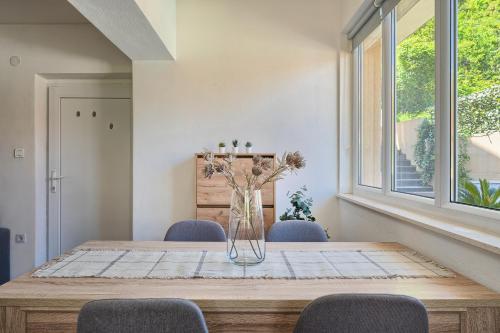 a dining room table with chairs and a vase with flowers at RELAX apartment Split area with private jacuzzi on terrace with mountain view in Srinjine