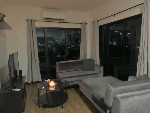 ein Wohnzimmer mit einem Sofa, einem TV und einem Fenster in der Unterkunft Room 36 Serviced Appartment - Skyline View in Bangkok
