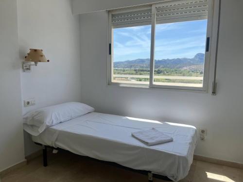 een witte kamer met een bed en een raam bij Bitacora VI Solo Familias SERVIPLAYA in Playa de Gandia