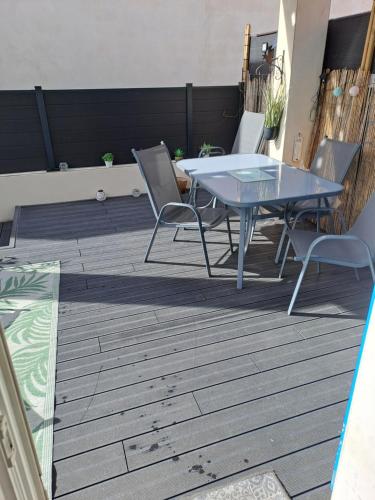 un patio avec une table et des chaises sur une terrasse dans l'établissement Maison en bord de mer, à Valras-Plage