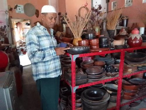 a man standing next to a shelf of pots and pans at Nan Bungalows Tetebatu in Tetebatu
