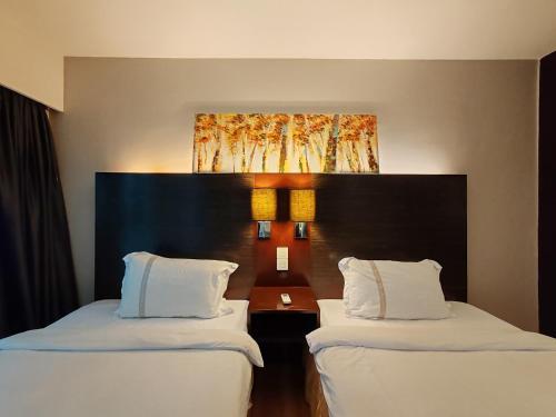 a hotel room with two beds with white pillows at Greenage MingSuite 明绿时代套房 Kota Kinabalu 亚庇市中心 in Kota Kinabalu