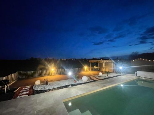 a swimming pool at night with a house and lights at L'hérisson LOPIC in Cours-de-Pile