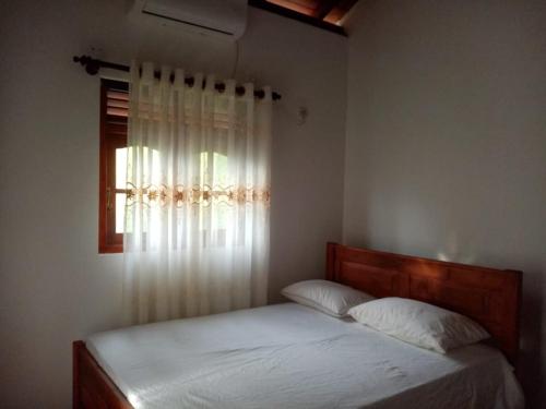 a bedroom with a bed and a window with white sheets at Sunsignvilla in Ahangama