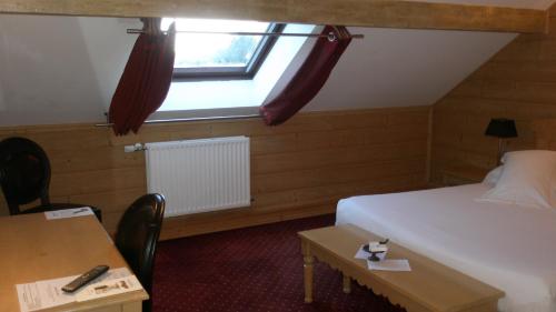 a room with a bed and a window and a table at Hôtel Restaurant Spa Les Jardins De Sophie in Xonrupt-Longemer