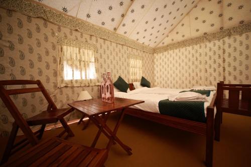 アラハバードにあるShivadya Camps MAHAKUMBH Melaのベッドルーム1室(ベッド1台、テーブル、椅子付)