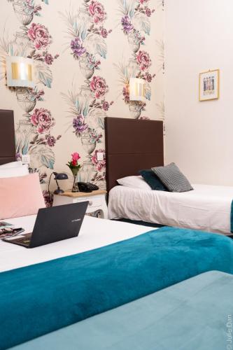 a room with two beds with a laptop on top of them at Hotel Mirabeau in Tours