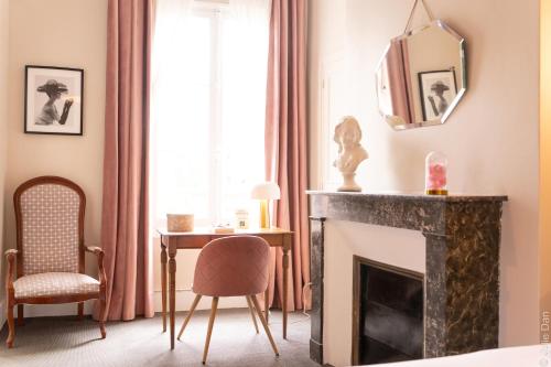 a room with a fireplace and a table and a mirror at Hotel Mirabeau in Tours