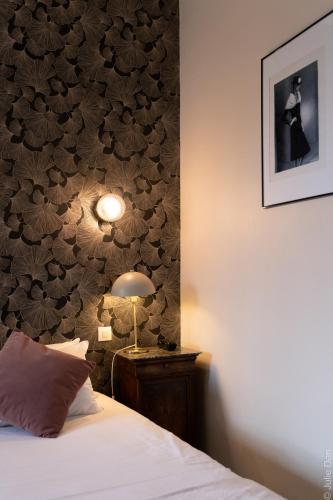 a bedroom with a bed and a wall covered in leaves at Hotel Mirabeau in Tours