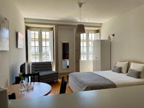 um quarto com uma cama, uma cadeira e uma mesa em Douro River Cozy Flats no Porto