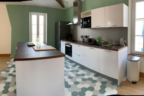 une cuisine avec des armoires blanches et un comptoir dans l'établissement Maison de ville avec terrasse, à Saint-Denis-dʼOléron