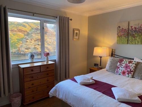 a bedroom with a bed with a window and a dresser at Cuckoos Rock in Graver