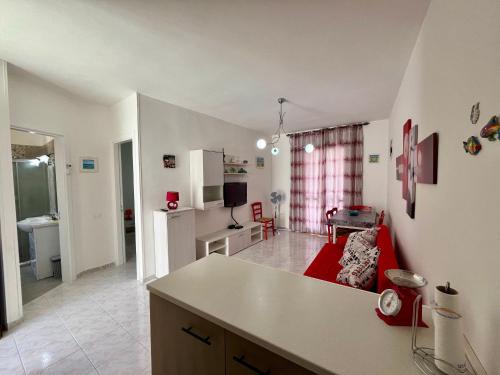 a kitchen and a living room with a red couch at LE DUNE Casa vacanze Salento Puglia in Torre dell'Orso