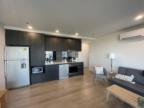 cocina y sala de estar con sofá y nevera en Spacious 2 bedroom apartment-free parking-pool-gym-wi-fi, en Belconnen