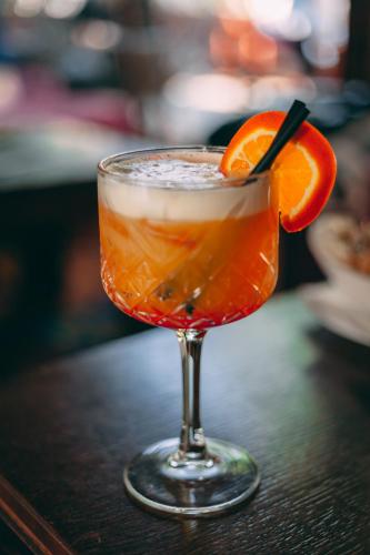 a drink in a glass with an orange slice on a table at Pansion Oscar Summer Garden in Mostar