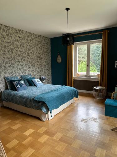 - une chambre avec un lit doté de draps bleus et une fenêtre dans l'établissement Au Ch'Alex, à Busset