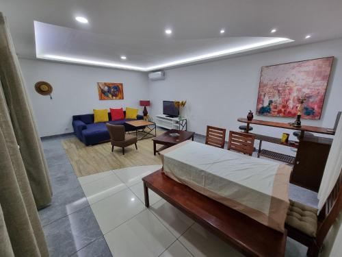 a bedroom with a bed and a living room at Appartements MAXIMA in Libreville