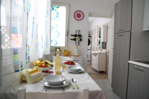 een witte keuken met een tafel met fruit erop bij Casa Vacanze La Coccinella in Trapani