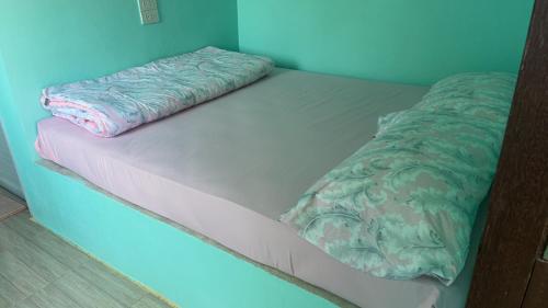 a unmade bed in a blue room at BAN SUAN KRATOM CAFE AND RESORT in Nakhon Pathom