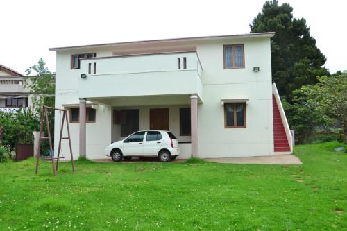 a white car parked in front of a house at Caron Niron Two Bedroom Villa in Kodaikānāl