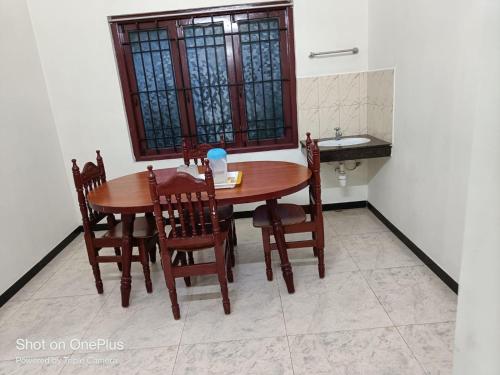 a wooden table and chairs in a kitchen with a sink at Caron Niron Two Bedroom Villa in Kodaikānāl