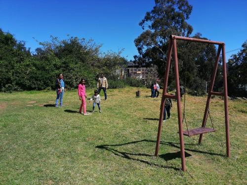 a group of people standing in a field with a swing at Caron Niron Two Bedroom Villa in Kodaikānāl