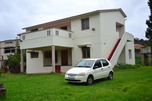 a white car parked in front of a house at Caron Niron Two Bedroom Villa in Kodaikānāl