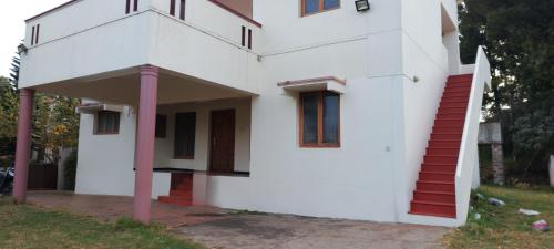 a white house with red doors and windows at Caron Niron Two Bedroom Villa in Kodaikānāl